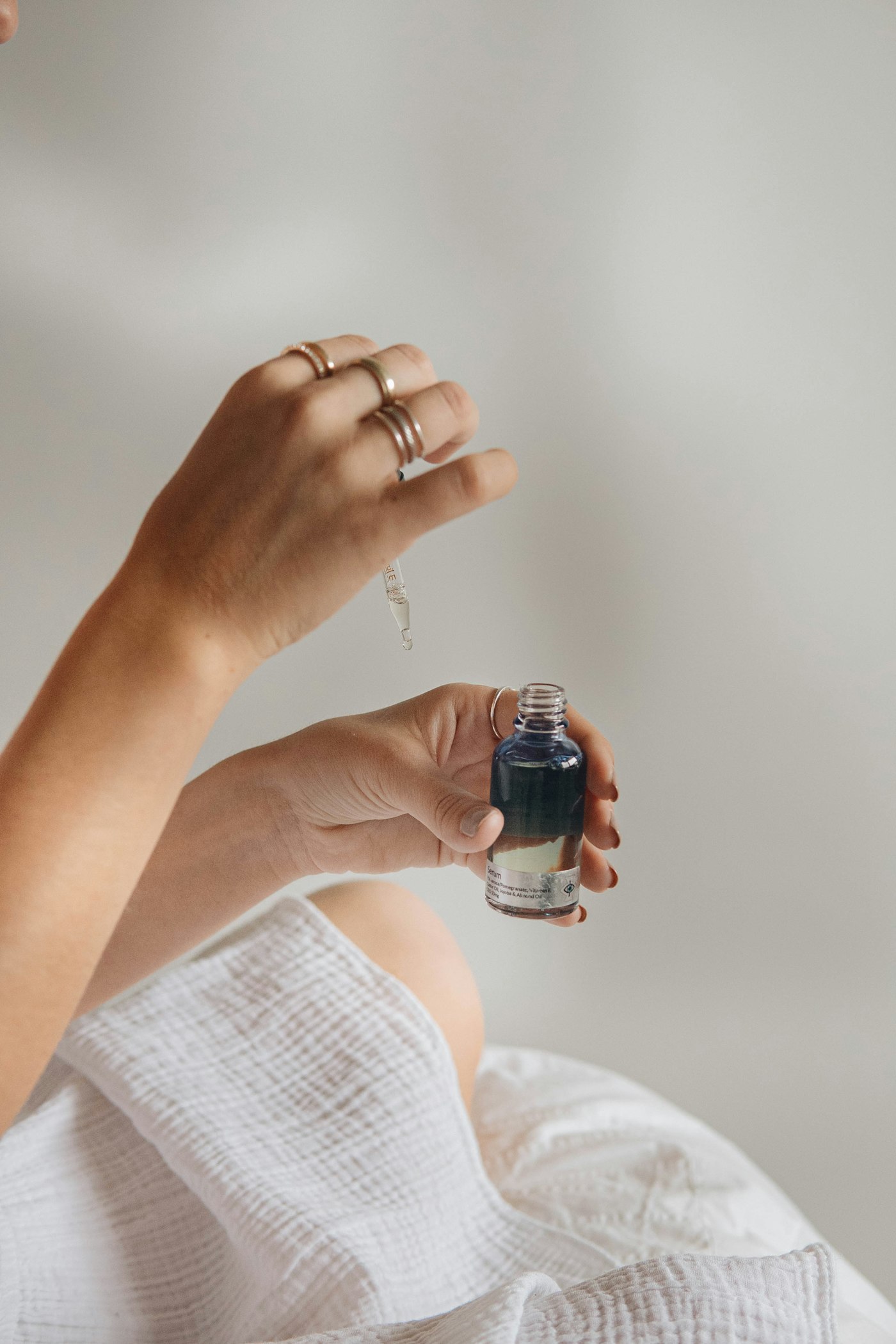 Hand holding a small glass bottle of facial oil