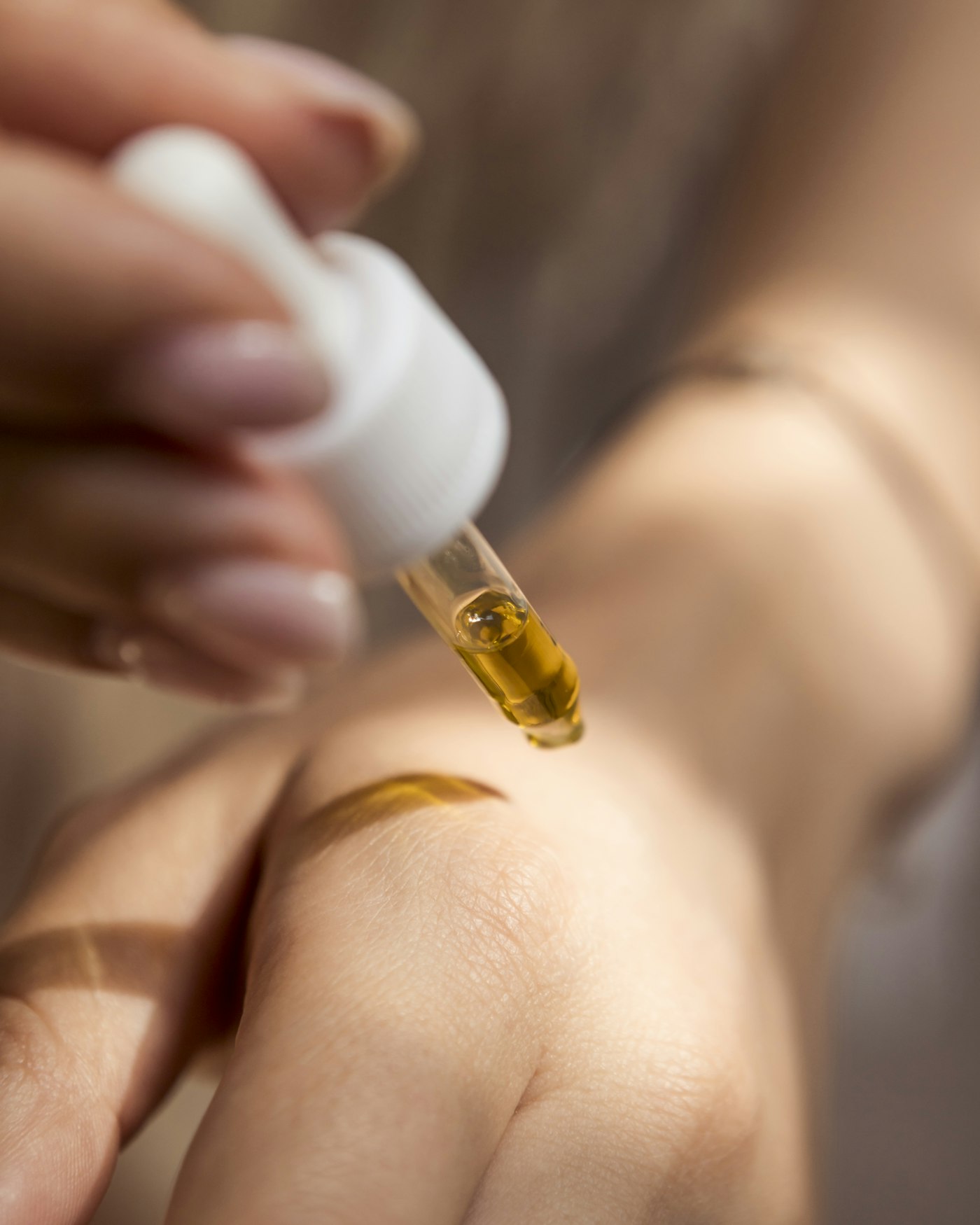 Golden facial oil dropped onto the back of a hand