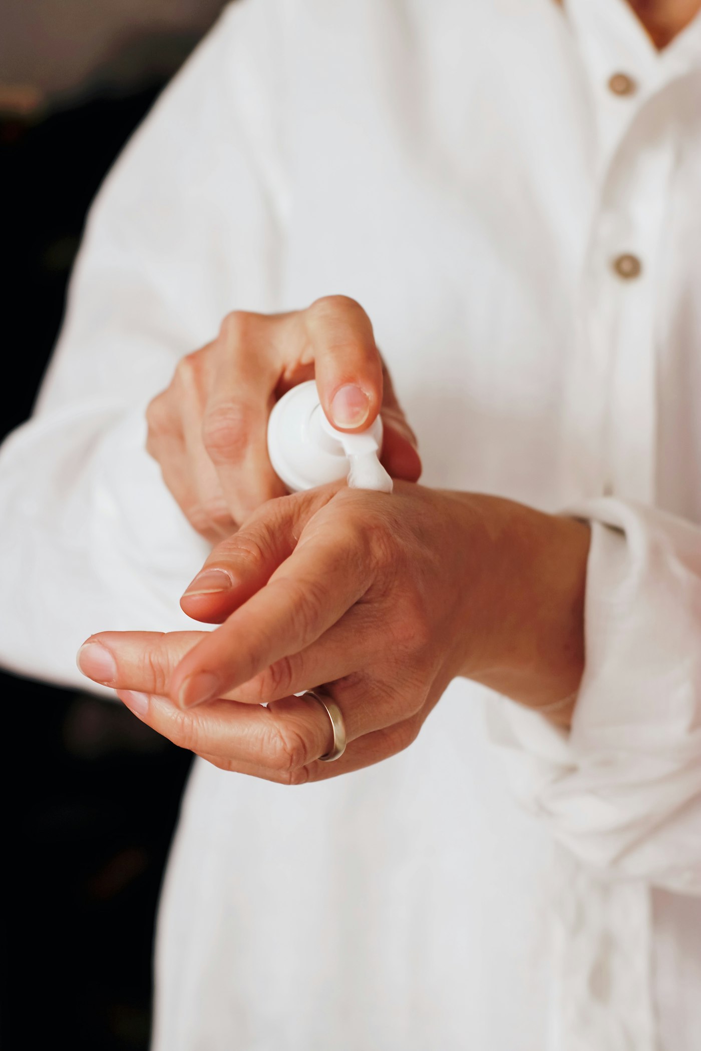 Hands applying lotion from a pump bottle